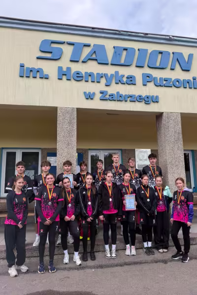 Drużyna sportowców z medalami przed Stadionem im. H. Puzonia w Zabrzegu. Fotografia.