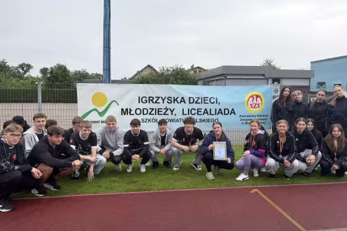 Uczniowie Liceum w Kozach kucają przed banerem