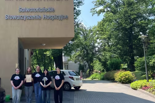 Fotografia: Pięć os&oacute;b przed hospicjum im. św. Jana Pawła II; jedna trzyma certyfikat.