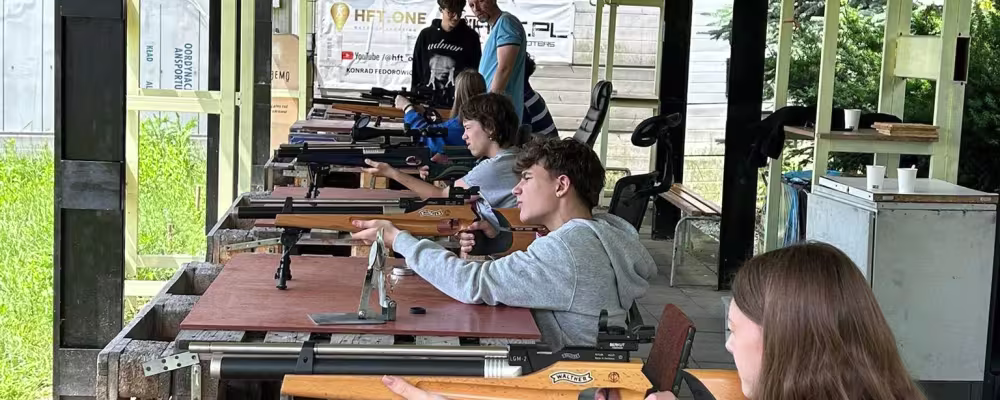 Młodzież uczy się strzelać z karabin&oacute;w na zadaszonej strzelnicy.